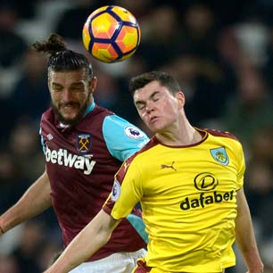 Andy Carroll jumps for a header with Michael Keane