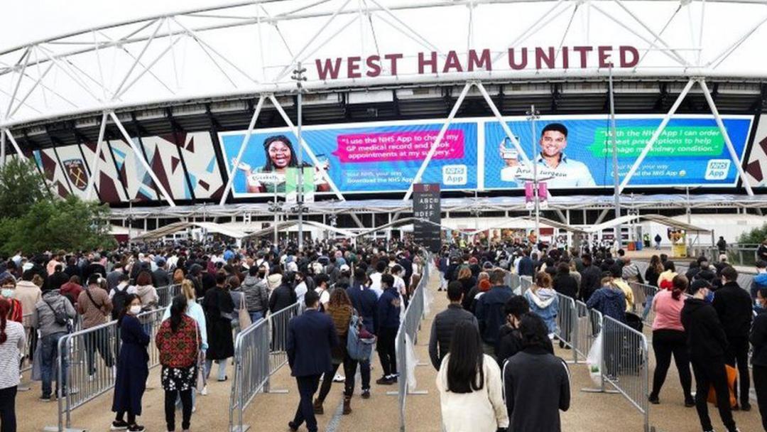 People queue for a COVID vaccination at London Stadium