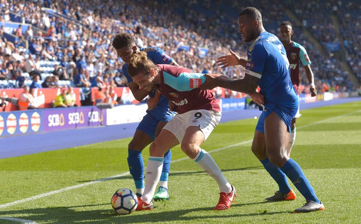 Andy Carroll holds off two Leicester City players at the King Power Stadium
